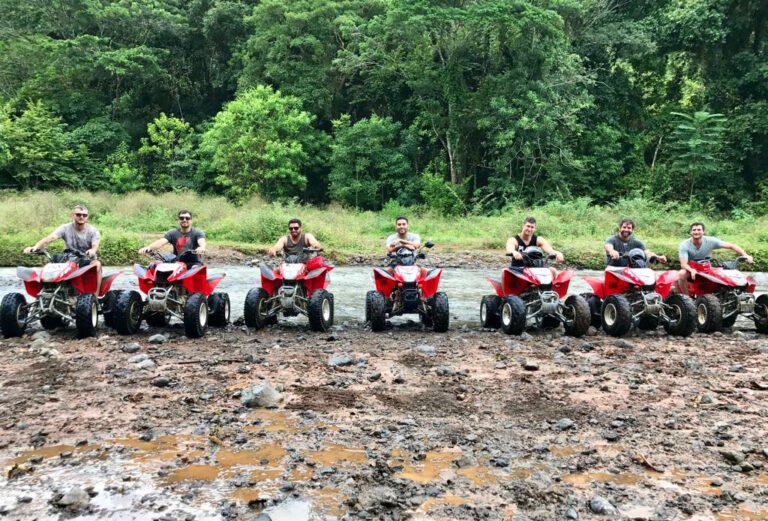 Line of red ATVs parked on the rocky riverbed during the ride