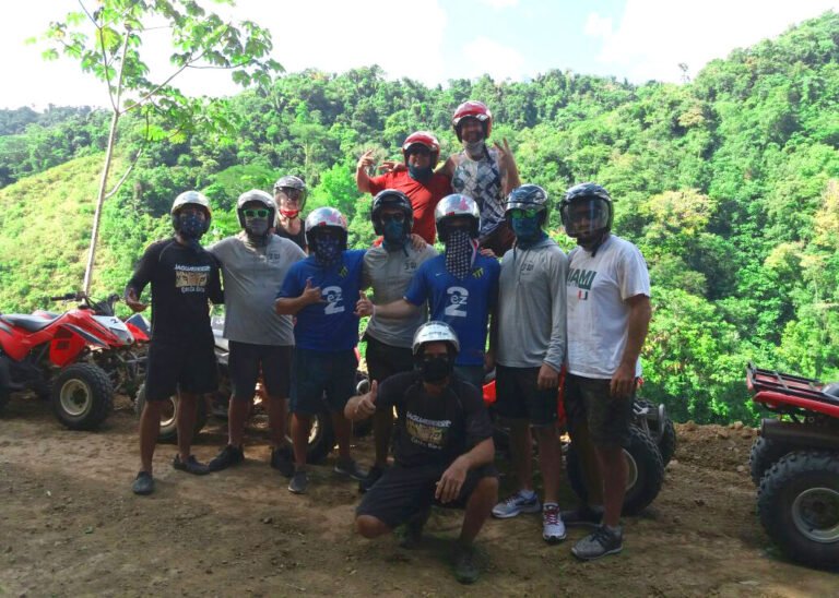 Group of riders with their ATVs on a hilltop above the jungle