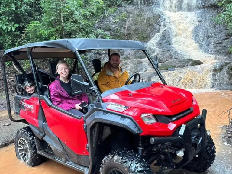 Family in a UTV parked at the foot of a waterfall