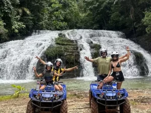 A group of Jaco ATV riders posing with the Jaguar waterfalls in Costa Rica in the background