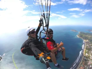 Two boys flying in a tandem paraglider over Jacó beach in Costa Rica