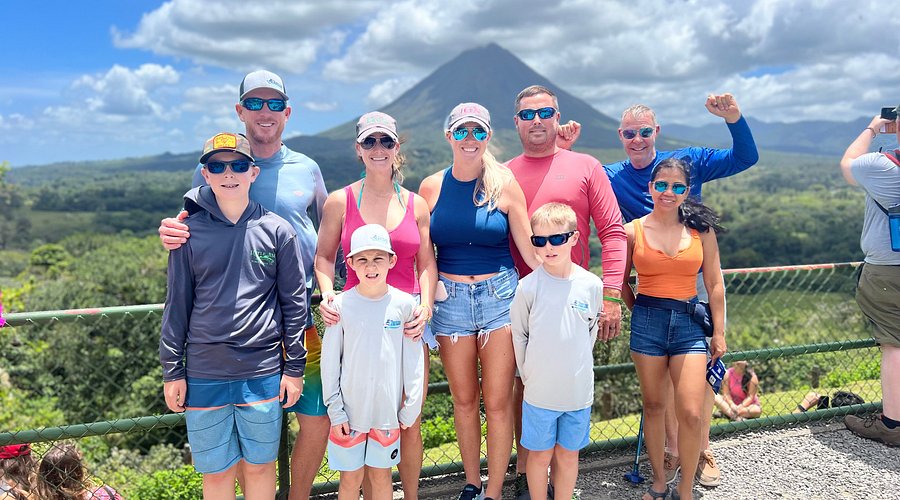 A family vacation group in Costa Rica with Arenal volcano behind them