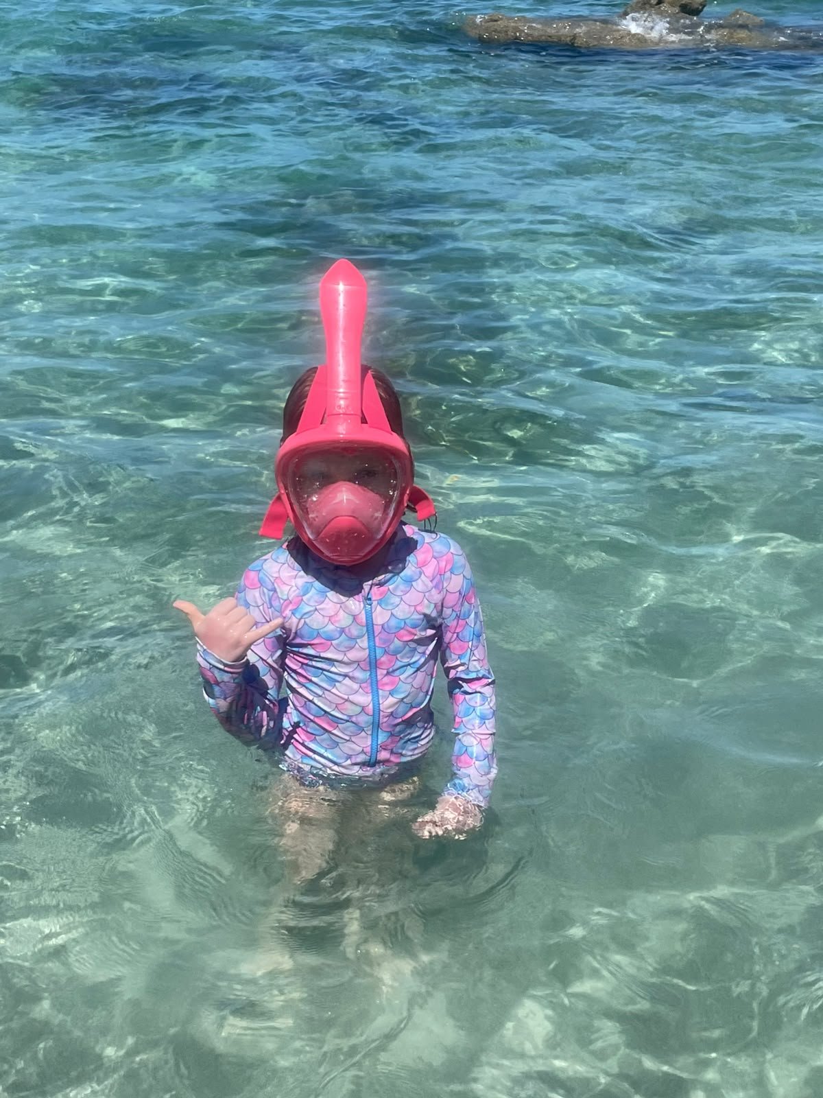 Child snorkeling in clear turquoise water at Playa Mantas
