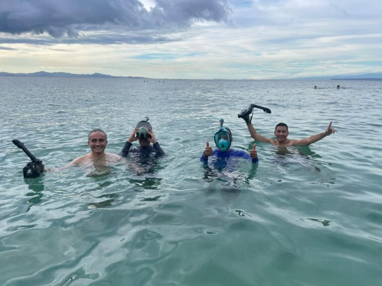 Group of four guests floating in the water at Playa Mantas holding their snorkel masks