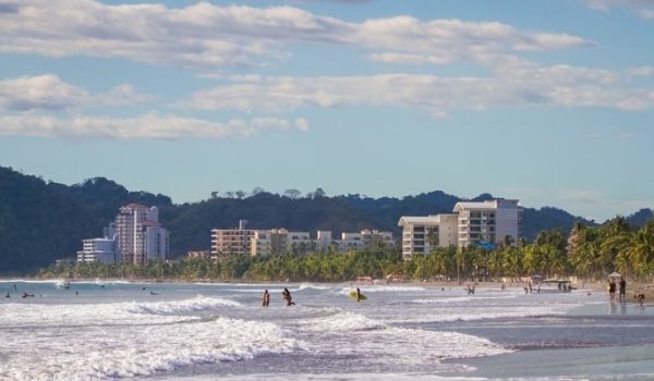 Scenic view of Jaco Beach with people on the water and some buildings in the background